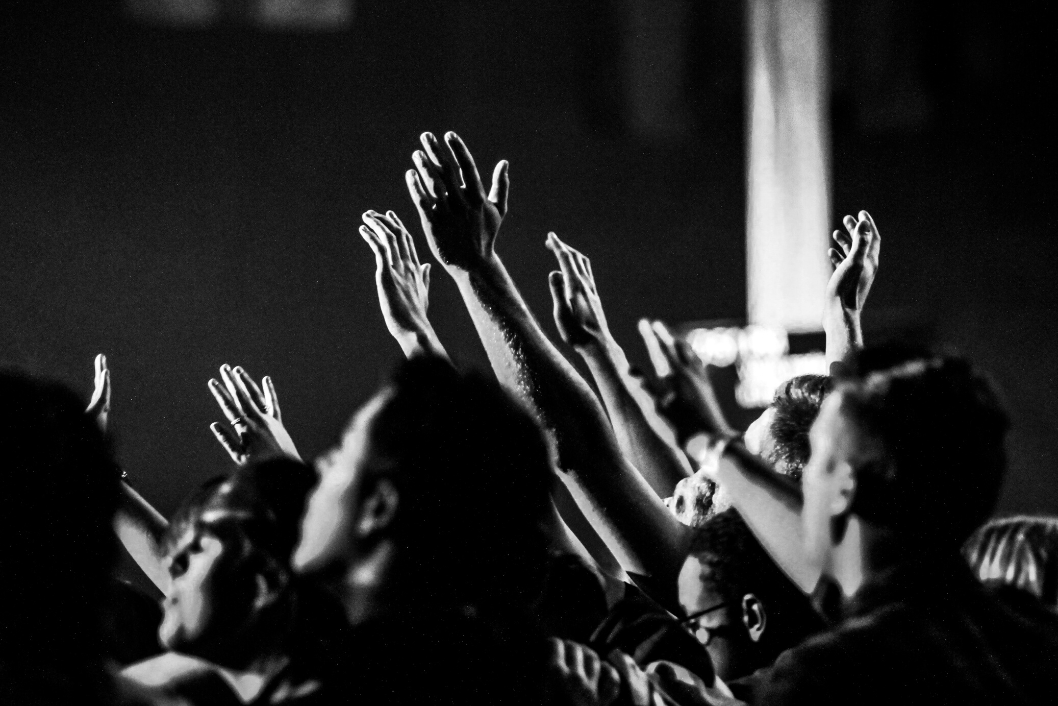 Grayscale Photo of People Raising Their Hands